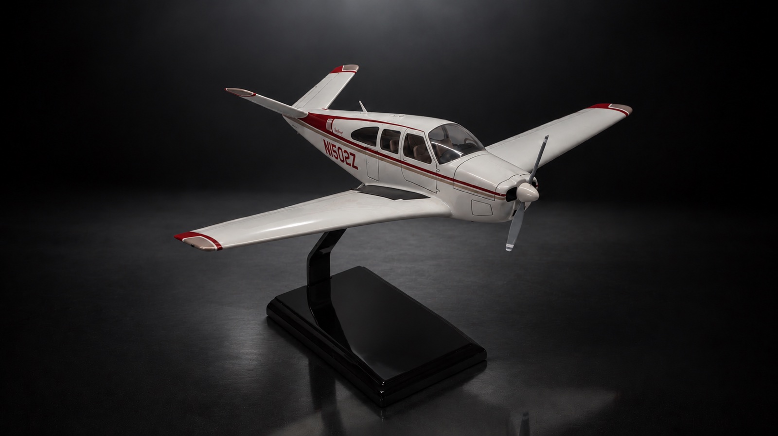 A white and red Beechcraft Bonanza scale model on a display stand