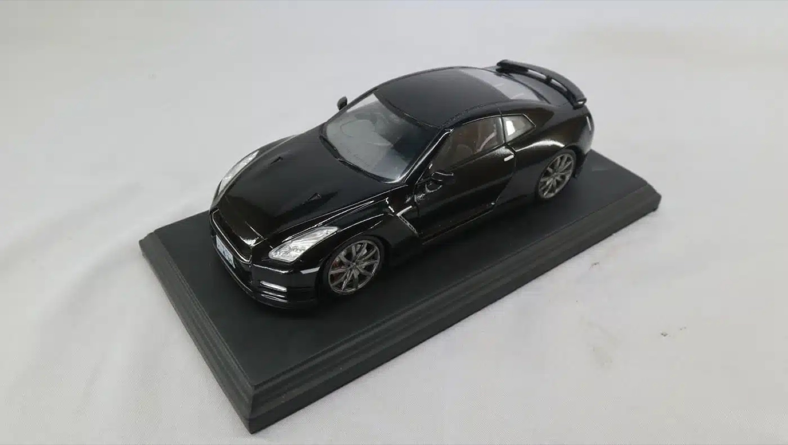 A hand-finished scale model of a black Nissan GT-R on a display plinth